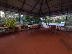 a dining room with tables and chairs and windows at Gothra Beach Casa in Alleppey