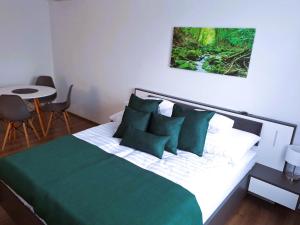 Un dormitorio con una cama verde y blanca y una mesa en Happy Home Apartman, en Miskolctapolca
