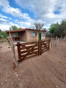 una pequeña casa detrás de una valla de madera en un campo en Ganesha Casa Vacacional en Las Rabonas