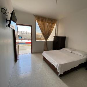 1 dormitorio con cama y ventana grande en Hotel La Mansión del Sol, en Tuluá