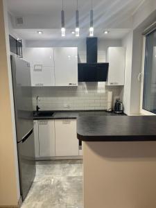 a kitchen with white cabinets and a black counter top at Apartament Górczyn 18 HGS Home in Gorzów Wielkopolski
