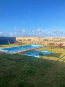 une grande piscine au milieu d'un champ dans l'établissement Amigos do Vento Pousada e Kite Point, à Touros