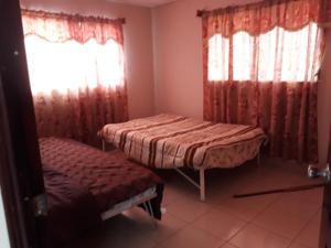 Zimmer mit 2 Betten und einem Fenster mit Vorhängen in der Unterkunft La Casa de Eyi 