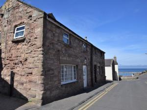 an old stone building on the side of a street at 2 Bed in Seahouses CN116 in Seahouses
