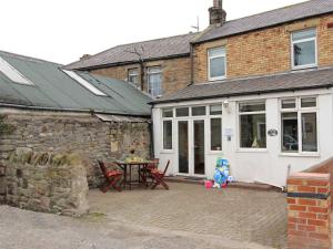 ein Haus mit einer Terrasse mit einem Tisch und Stühlen in der Unterkunft 2 Bed in Seahouses CN146 in Seahouses