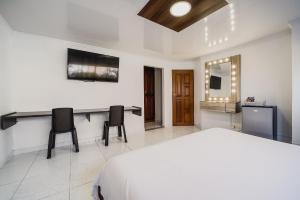 a bedroom with a bed and a desk and two chairs at Villa Santos Apartaestudios in Barranquilla