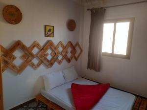 a small bedroom with a bed with a window at Boilers Surf House in Tamri
