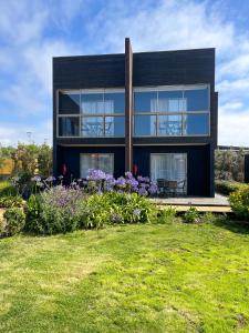 Una casa negra con flores delante. en Refugio Lobos, en Pichilemu