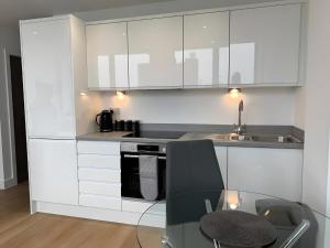Una cocina con gabinetes blancos y una mesa de vidrio. en Amazing Views of the City, en Mánchester