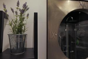 un vase avec des fleurs violettes sur une étagère à côté d'un miroir dans l'établissement Hotel Liberty, à Levico Terme