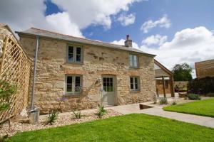a stone house with a green lawn in front of it at Barnwell Cottage *Stunning Cornish Cottage* Oozing Charm + Comfort in Cubert