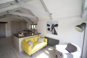 a living room with a yellow couch and a chair at Barnwell Cottage *Stunning Cornish Cottage* Oozing Charm + Comfort in Cubert