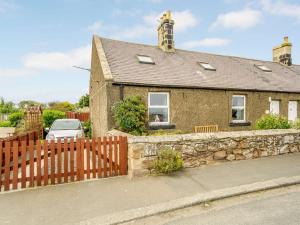 a brick house with a wooden fence in front of it at 2 Bed in Boulmer 60464 in Boulmer