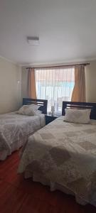 two beds in a bedroom with a window at Casa en la serena in La Serena