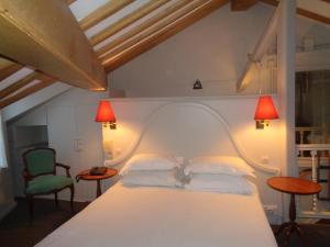 a bedroom with a white bed with two lamps and two chairs at Hôtel les Degrés de Notre Dame in Paris