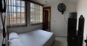 um quarto com uma cama branca e uma janela em Hotel Sangil Tuluá em Tuluá