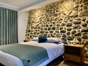 Casa Encuentro San Blas في كوسكو: غرفة نوم بحائط حجري وسرير