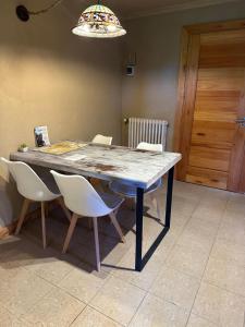 stół jadalny z białymi krzesłami i oświetleniem w obiekcie Le Bouquet Apart Hotel w mieście Bariloche
