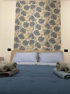 a bedroom with a bed with blue sheets and a wallpaper at Aliss Home ASSISI in Bastia Umbra