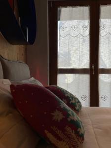 a bed with two pillows on it with two windows at Maison Rododendro Elegant in Breuil-Cervinia