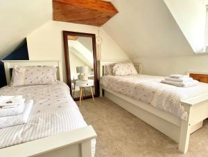 - deux lits dans une chambre mansardée avec un miroir dans l'établissement Bumblebee Cottage - Cosy Cottage in Area of Outstanding Natural Beauty, à Hemel Hempstead