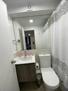 uma casa de banho com um WC branco e um lavatório. em Departamento nuevo en Villarrica em Villarrica