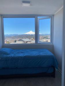 um quarto com uma cama azul e 2 janelas em Departamento nuevo en Villarrica em Villarrica