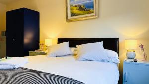 a bedroom with a bed with white sheets and pillows at West Strand Beach Penthouse, Portrush Seafront in Portrush