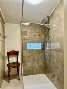 a bathroom with a shower with a wooden chair at Villa Bergruh in St. Gallen