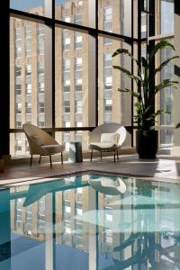 a swimming pool in a building with two chairs at Raffles Boston in Boston
