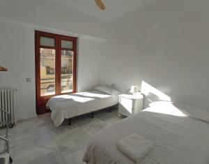 two beds in a white room with a window at Entre la Estación y el Ayuntamiento in Valencia