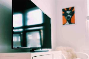 a television sitting on top of a dresser with a window at London Flat next to Central Line Underground Station in London