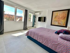 sypialnia z łóżkiem, telewizorem i oknami w obiekcie Laureto BnB w mieście Roquebrune-Cap-Martin