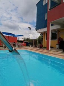 a blue swimming pool next to a building with umbrellas at Pousada TOP in Mairiporã