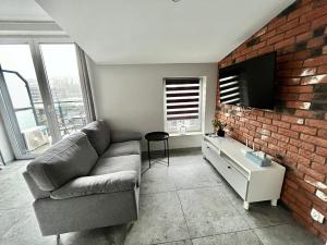 a living room with a couch and a brick wall at City Center Apartments z parkingiem in Bydgoszcz