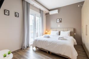 een slaapkamer met een wit bed en een groot raam bij More Athens Apartments in Athene