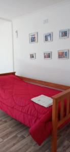 a red bed in a room with pictures on the wall at Los tordos posada in Puerto Madryn