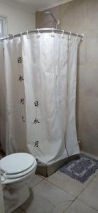 a bathroom with a toilet and a shower curtain at Los tordos posada in Puerto Madryn
