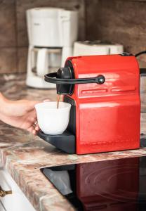 a person is pouring coffee into a red toaster at VB36 Vendégház in Villány