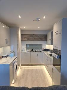 a kitchen with white cabinets and a wooden floor at Royal Atlantic View Apartment in Portrush