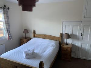 a bedroom with a bed with white sheets and two lamps at The Cromwell Arms Inn in Bovey Tracey