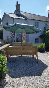 a wooden bench with an umbrella in front of a house at The Cromwell Arms Inn in Bovey Tracey