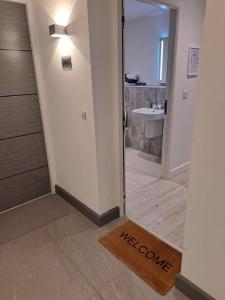 a bathroom with a sink and a door with a welcome mat at Royal Atlantic View Apartment in Portrush