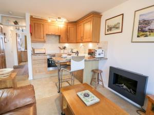 a living room with a kitchen with a fireplace at 48A South Snowdon Wharf in Porthmadog