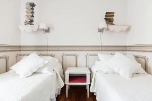 two beds with white sheets and a side table at Spacious, Air Conditioner, Few Minutes to the Castle in Malcesine