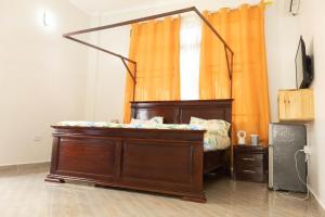 ダル・エス・サラームにあるMorris Multiのオレンジ色のカーテンが備わるドミトリールームのベッド1台分です。