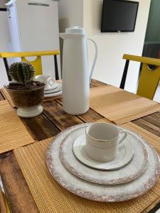 una mesa con una taza y un jarrón. en Aldeia das Águas Park Resort - Quartier - Flat B102 en Barra do Piraí