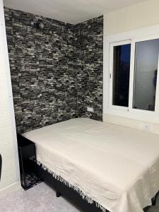 uma cama num quarto com uma parede de tijolos em Casa Oso em Vilanova i la Geltrú