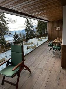 terraza con silla verde y mesa en el balcón en Renovated Mountain View Apartment - Les Eperviers, en Crans-Montana