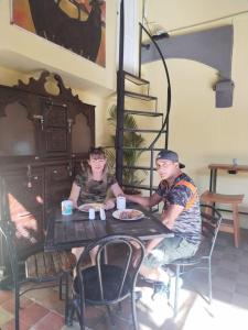 dos hombres sentados en una mesa con una pizza en Hostal Don Gato en Granada